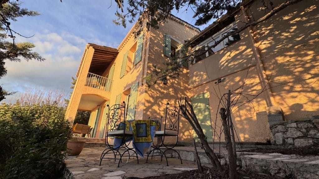 vu des exterieurs de la villa overdon avec facade au soleil et terrasse vu de la terrasse coté jardin de la villa overdon, photo de l architecture de la villa et du salon de jardin cosy