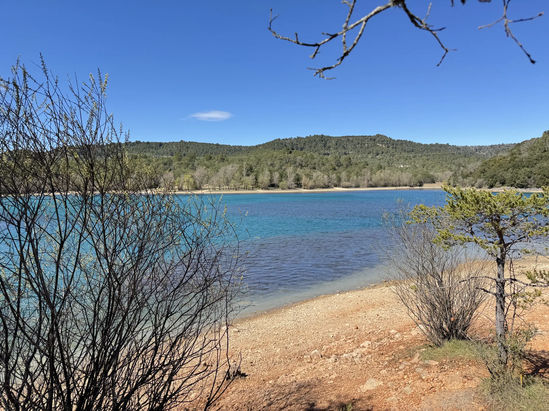 Arrivée au lac de Montpezat avec ses eaux turquoise vues à travers les branches Arrivée au lac de Montpezat avec ses eaux turquoise vues à travers les branches